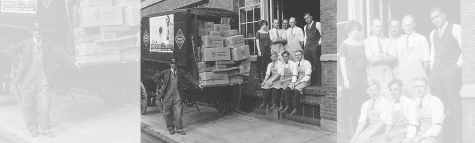 Black and white photo of group of employees next to a delivery carriage full of boxes