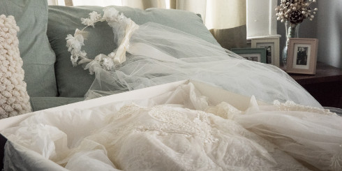 Wedding dress in box with veil on bed